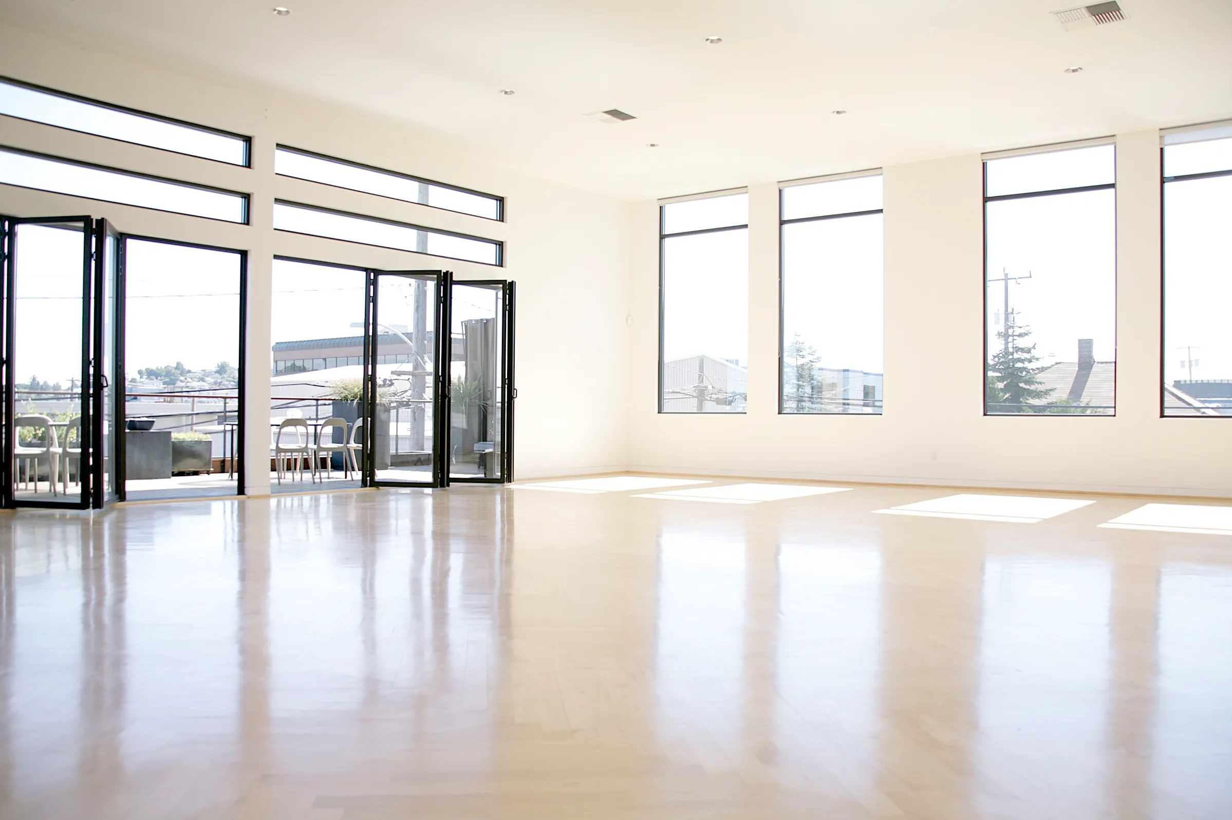 Wide view of the Light Loft event venue in Seattle — open floor, folding doors to the deck and tall windows
