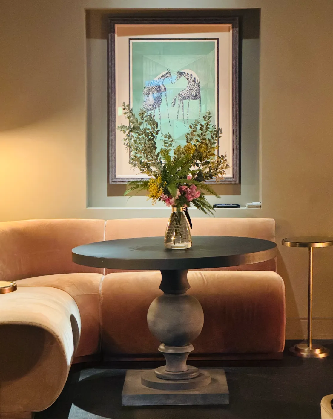 Lounge at the Light Loft in Seattle — pedestal table with flowers, framed artwork and velvet banquette